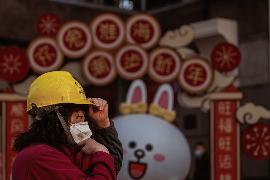 A woman stands in front of the decorations for the Chinese New Year in Shanghai. Covid-19 is expected to spread beyond the big cities during the celebrations around January 22nd. Photograph: Alex Plavevski/EPA