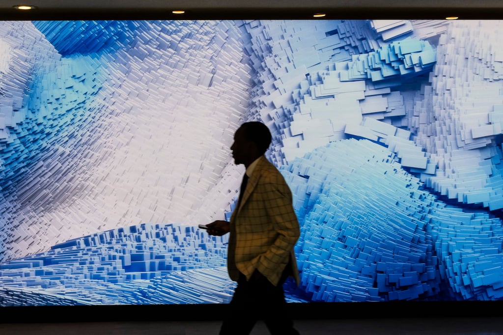 A person walking past an AI-generated video art installation entitled Large Nature Model: Coral by artist Refik Anadol at the United Nations headquarters in New York. The study by consultancy Sia Partners shows the scale of the potential impact of AI on workers