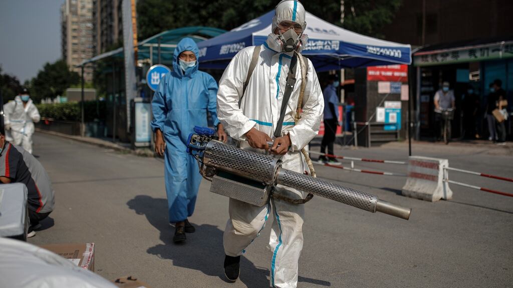 Workers wearing protective face masks and suits are seen as they carry out disinfection operations in a residential area near locked-down areas due to the Covid-19 outbreak in Beijing, China on Friday. Photograph: Stringer/EPA