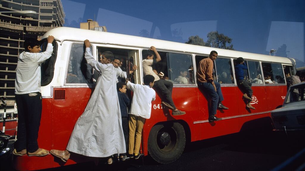Outriders cling to a bus in Cairo’s rush hour traffic, Cairo, Egypt. Photograph:  Winfield Parks/National Geographic/Getty Images