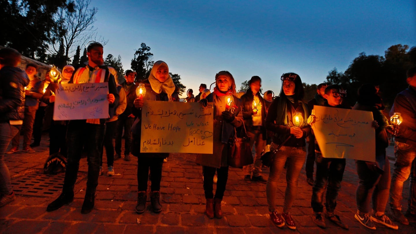 Syrians holding posters reading, ‘we want peace.. we love peace’ during a vigil at the Ummayyad Square in Damascus, in Syria, on Friday. Photograph: EPA