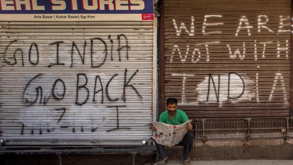 A Kashmiri man in front of closed shops covered with graffiti in the commercial hub of Srinagar city centre. Photograph: Yawar Nazir/Getty