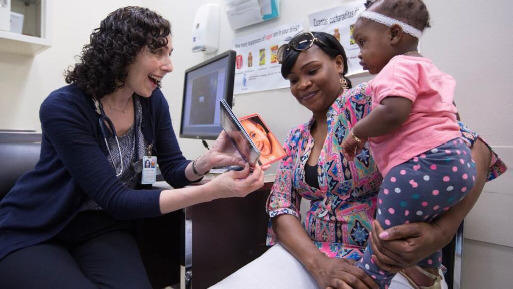 Dr Leora Mogilner shows a book to nine-month old Kaylee Smith and her mother, Tameka Griffiths, at Mount Sinai Hospital in New York. Photograph: Ruth Fremson/The New York Times