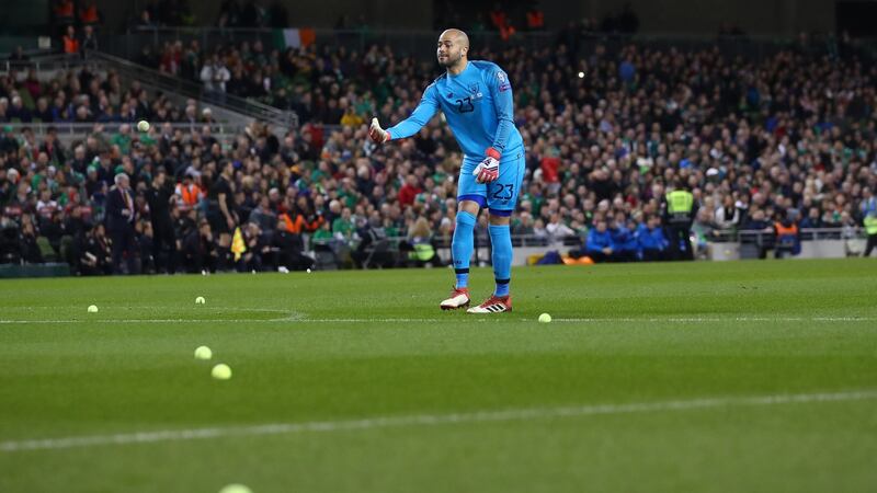 Darren Randolph removes tennis balls from the field after Irish fans’ protests. Photo: James Crombie/Inpho