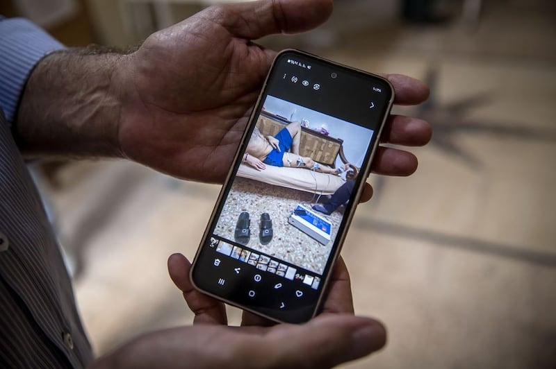 Samir Mansour holds up a photo of the injuries his son sustained during the Mar Elias bombing.