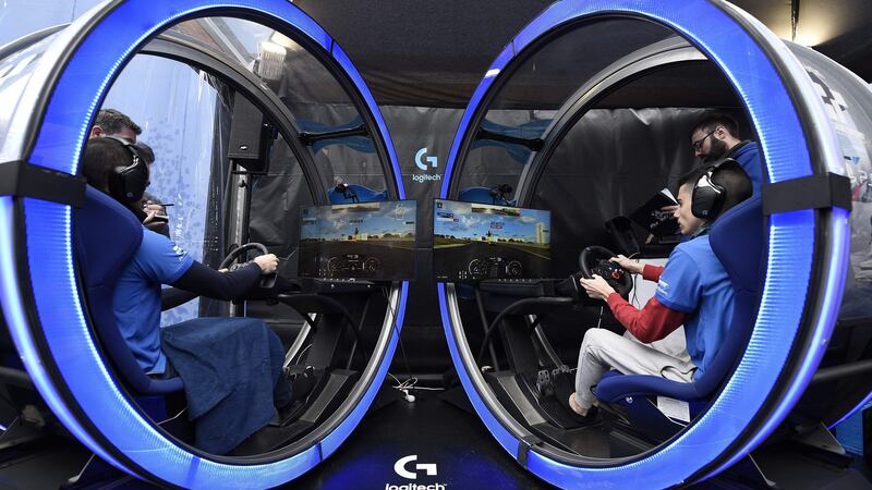 Attendees playing the Grand Prix Sport video game at the Logitech stand of the Mobile World Congress