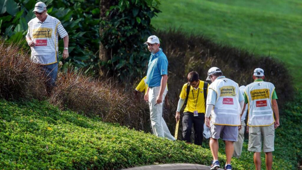 Peter Larwie searches for his ball during his four over par third round in the Malaysian Open. (Photograph: EPA/AZHAR RAHIM)