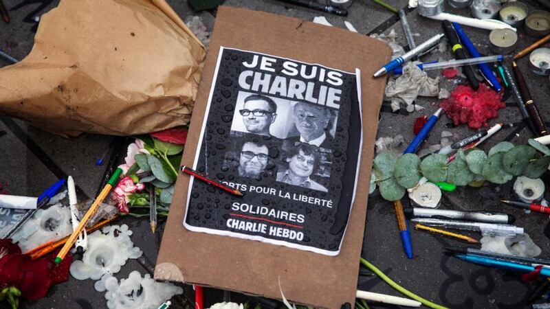 A poster reads ‘Je suis Charlie’ (I am Charlie) amid symbolic pens and pencils as people gathered for a minute of silence commemorating those killed in a shooting at French satirical magazine Charlie Hebdo, in Paris. Photograph: Etienne Laurent/ EPA