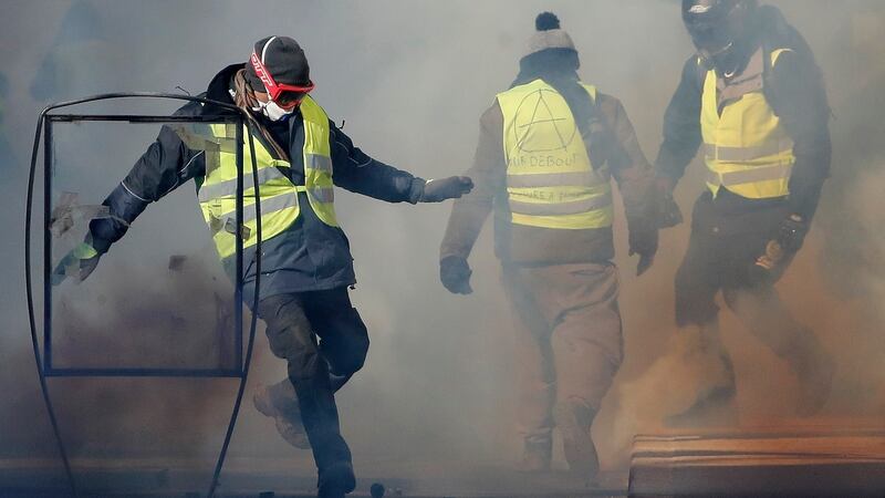 A protester in Nimes attempts to kick a tear gas canister towards police. Photograph: EPA