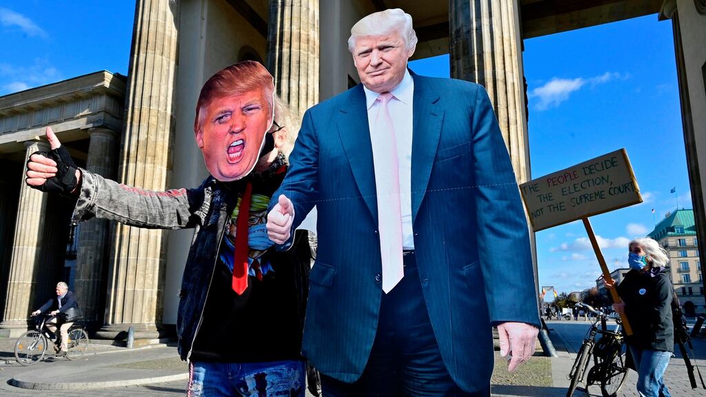 A supporter of US president Donald Trump in front of the Brandenburg Gate as a member of the Democrats Abroad organisation holds a placard urging that all ballots be counted, in Berlin. Photograph: John Macdougall/AFP via Getty
