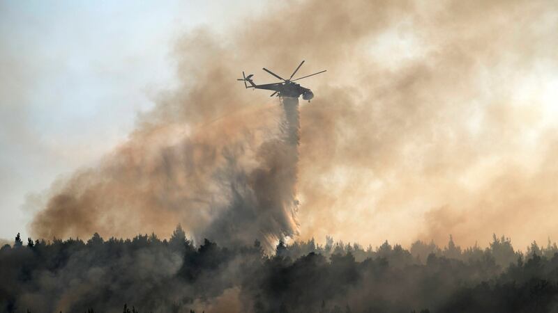 An helicopter drops water over a fire in Varibobi area, northern Athens, Greece. Photograph: Thanassis Stavrakis/AP Photo
