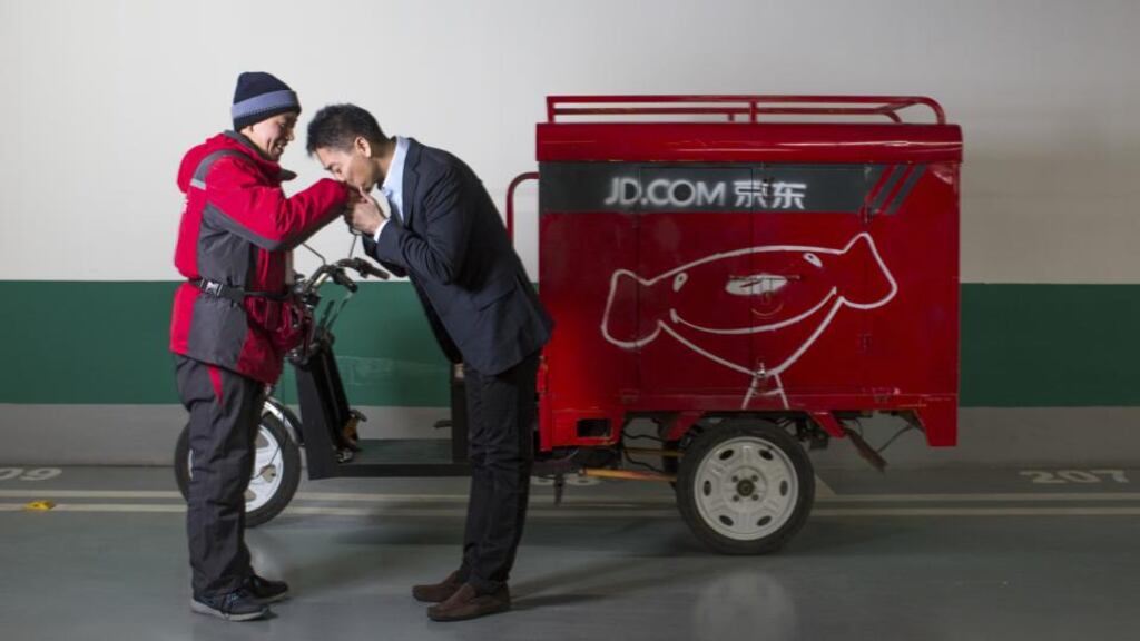 Richard Liu, chairman and chief executive of JD.com, playfully kisses the hand of employee Li Quan, as he borrows his delivery tricycle for some publicity. JD.com has emerged as a Chinese online goliath with a model that echoes that of Amazon. Photograph: Sim Chi Yin/New York Times