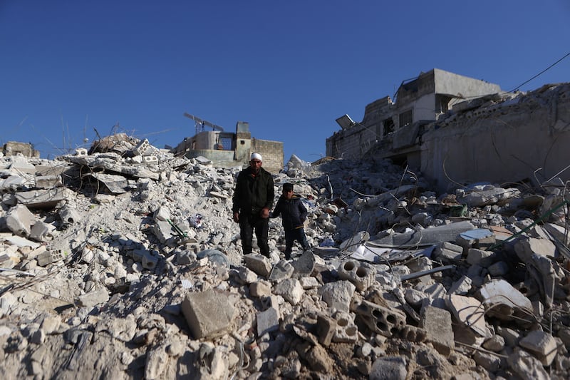 A Syrian man who lost most of his family members in last week's earthquake walks with one of his surviving sons above the rubble of their collapsed building in the village of Atarib, in the northwestern Aleppo province. Photograph Aaref Watad/AFP via Getty Images