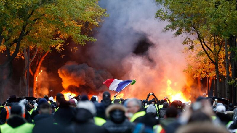 A French flag is seen as fires burn during a protest of yellow vests (gilets jaunes) against rising oil prices and living costs, on in Paris on Saturday. Photograph: Getty