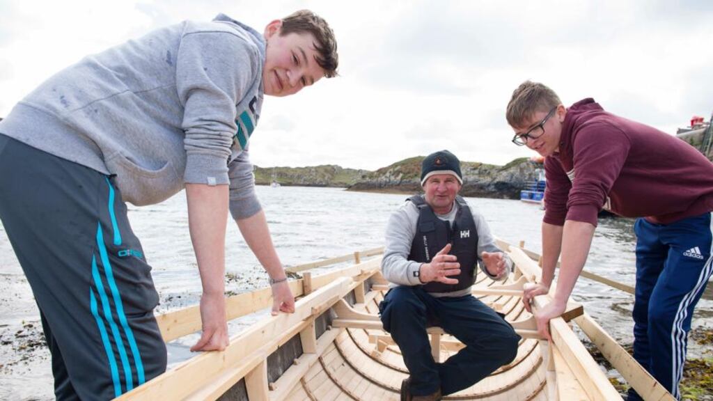Teenagers Mark Cunnane, and Niall Coyne, with master boatbuilder Pat Folan on an Inishbofin community currach. Photograph: Andrew Downes
