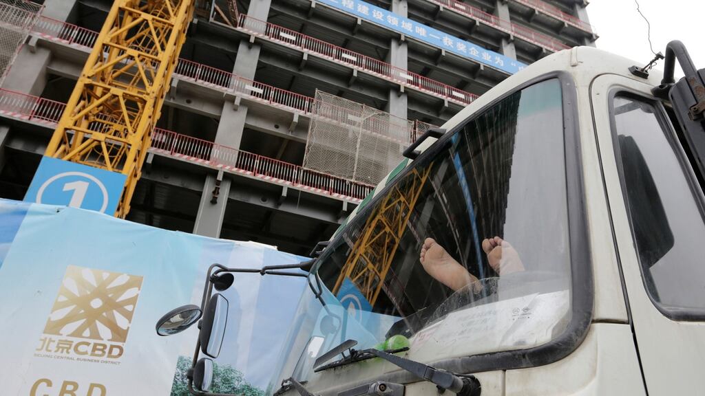 A driver rests in a construction engineering vehicle next to a construction site in Beijing’s central business district