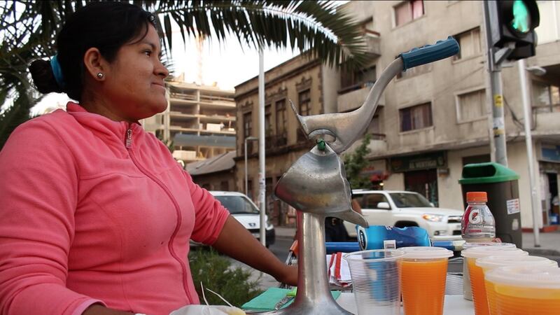Alicia, a Peruvian, sells orange juice on the street in Madrid.