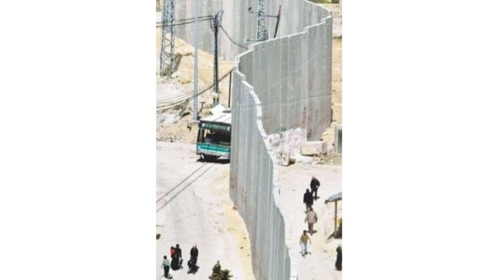 Palestinians walk next to part of Israel's security barrier in east Jerusalem yesterday.