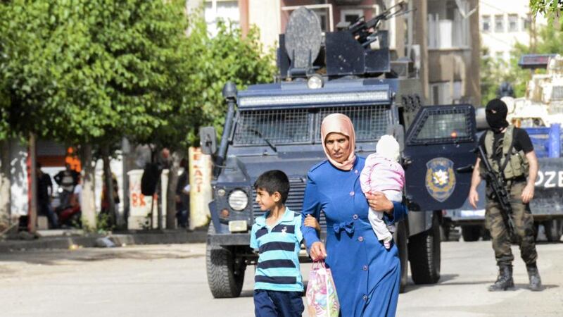 Police forces stand by as a woman and her children evade clashes between rival Kurdish groups in Diyarbakir, southeastern Turkey. Photograph: Ilyas Akengin/AFP/Getty Images