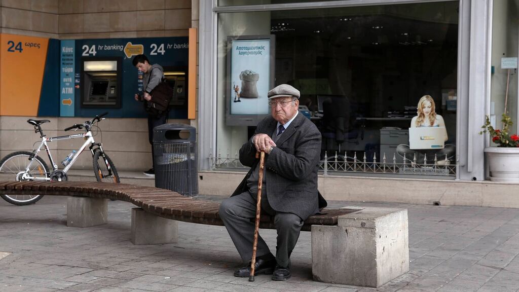 An elderly man sits in front of a closed branch of Bank of Cyprus as a youth makes a transaction at an ATM in Nicosia today. Labour MEP
Nessa Childers described as a “terrible mistake” a bailout deal which includes small Cypriot depositors. Photograph: Yorgos Karahalis/Reuters.