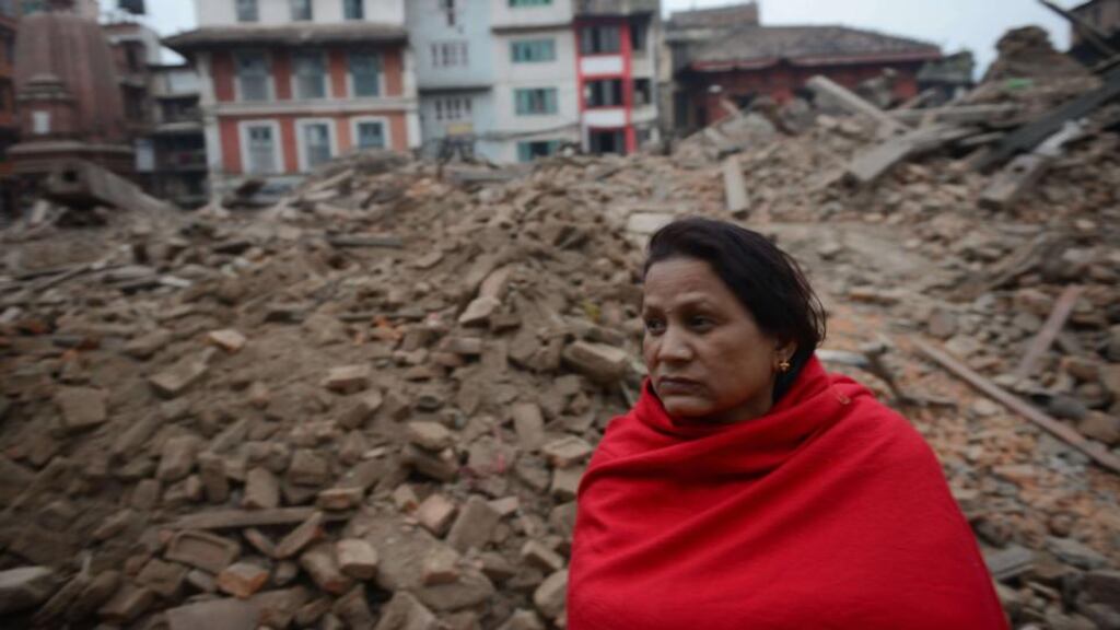 A Nepalese resident sits near buildings in Kathmandu that were severely damaged by the earthquake which occurred on Saturday morning. Photograph: Prakash Mathema/AFP/Getty Images.