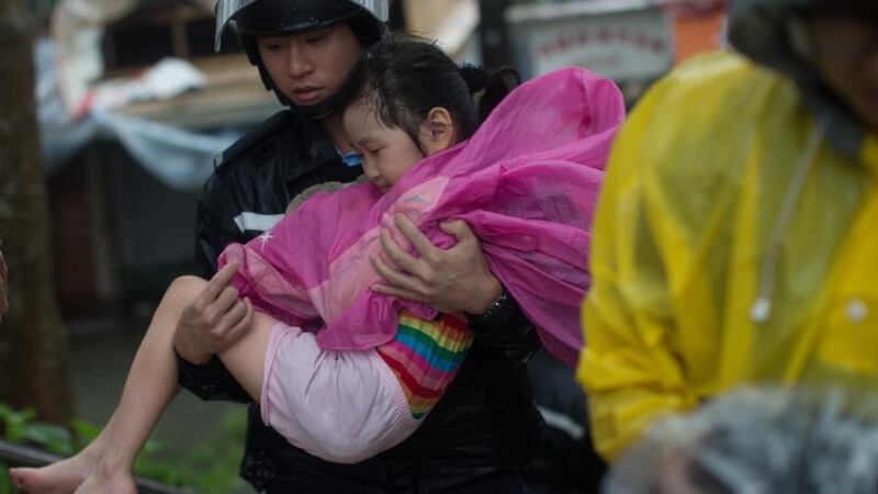 A police officer carries young girl to safety during Typhoon Mangkhut in Lei Yu Mun, Hong Kong. Photograph: Jerome Favre/EPA