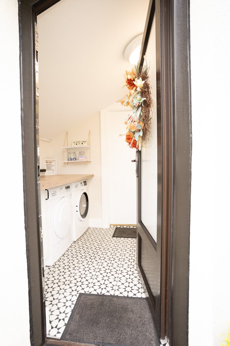 The entrance porch with decorative navy and white tiles. There is a deep countertop here, creating a handy utility space for the washing machine and dryer.