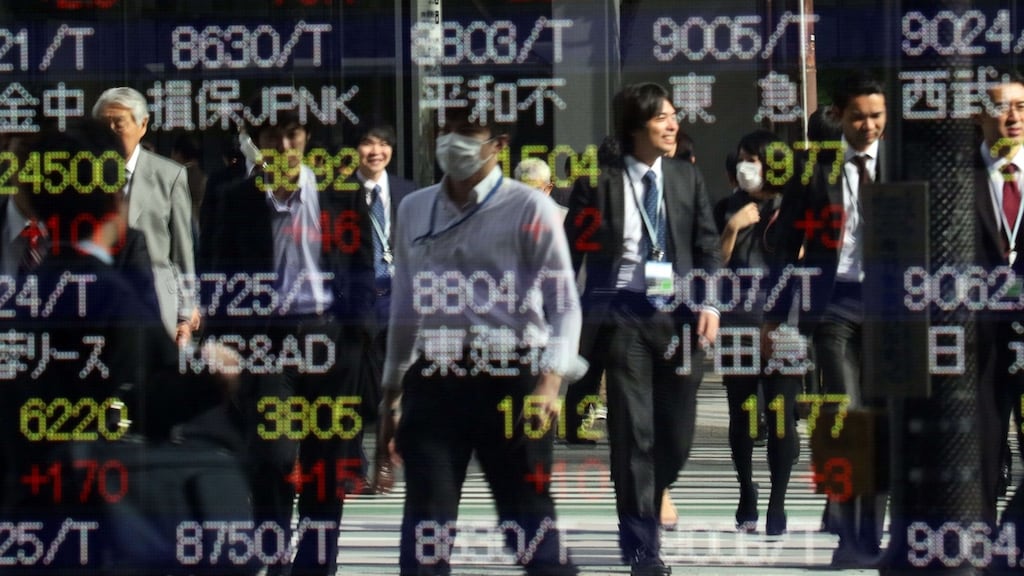 Pedestrians are reflected on a share prices board in Tokyo. Photograph: AFP/Getty Images