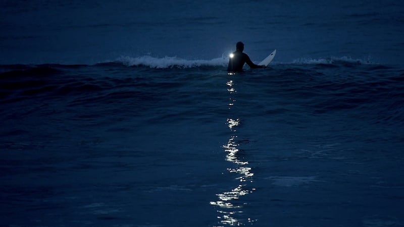 James McDonald from Ireland surfs under a full moon near San Diego. Photograph: Donald Miralle/The New York Times
