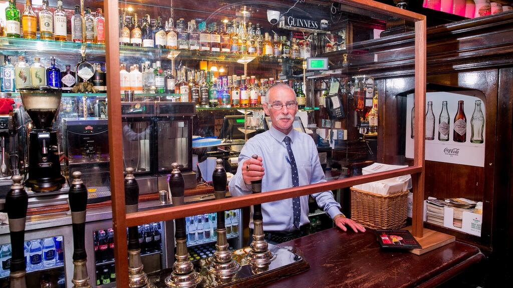 John O’Brien, manager of Doheny & Nesbitt, serving pints behind a perspex screen. Photograph: Gareth Chaney/Collins