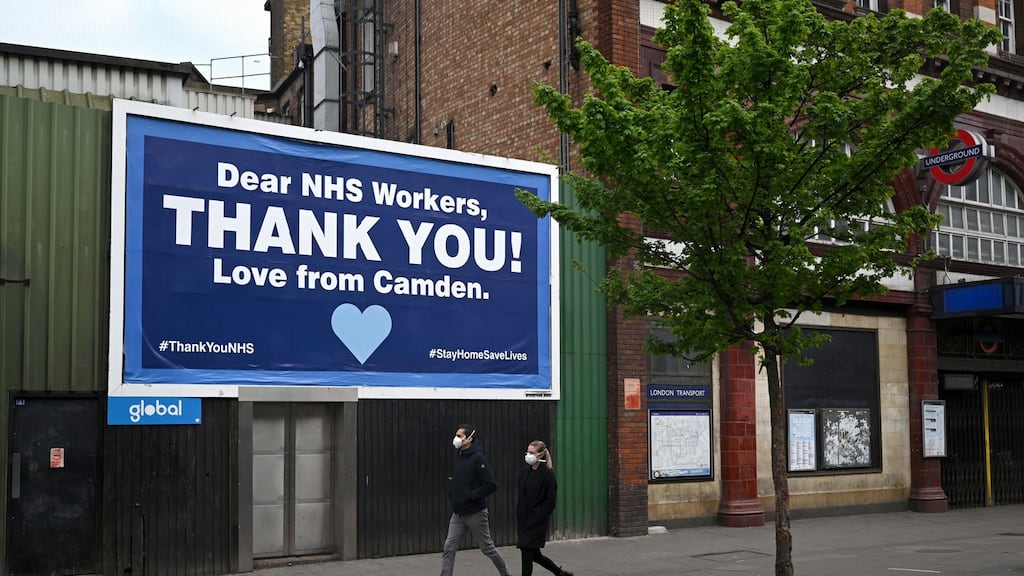 A masked couple passes a thank you message to Britain’s National Health Service (NHS) in Camden Town in London on Saturday. Photograph: Neil Hall/EPA