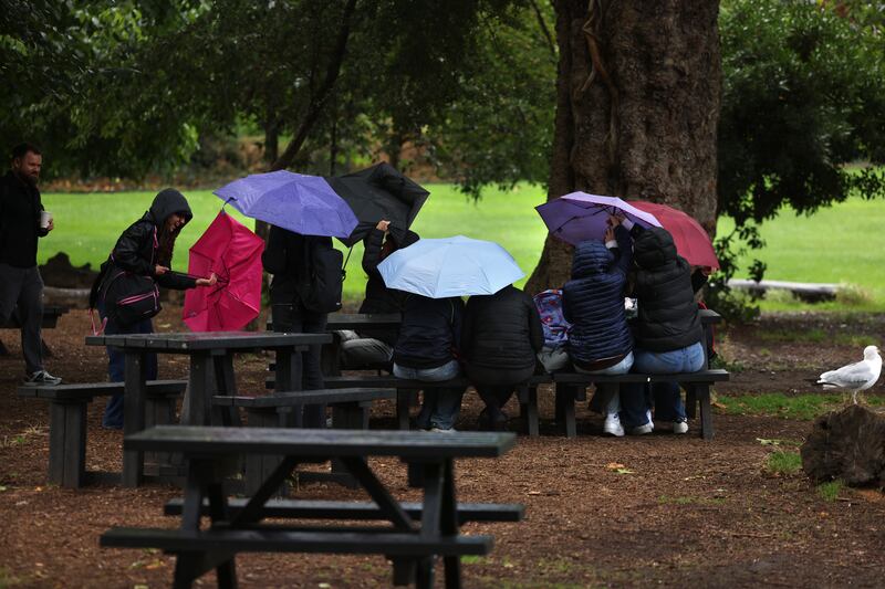 People taking cover under umbrellas and trees in Merrion Square, Dublin on Thursday. Photograph: Dara Mac Dónaill