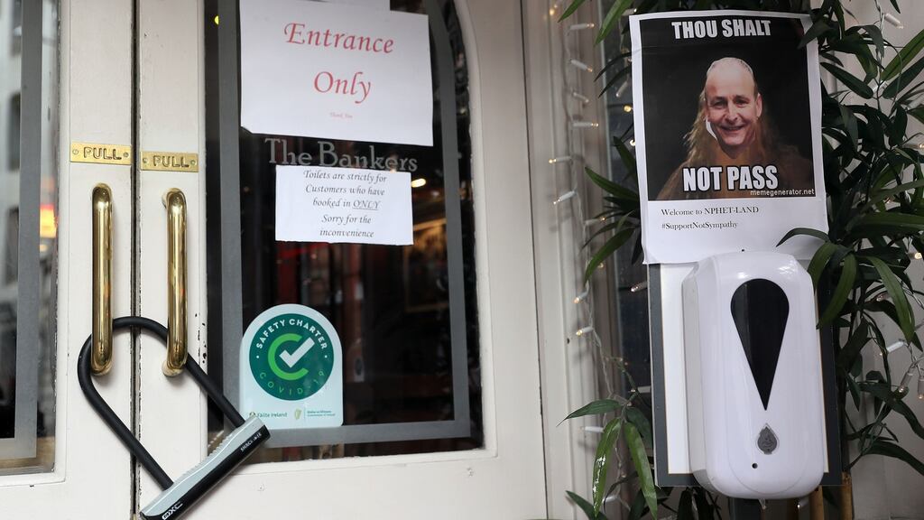 A photo of Taoiseach Micheál Martin is seen at the locked entrance to a pub in Dublin’s city centre.  Photograph: Brian Lawless/PA Wire