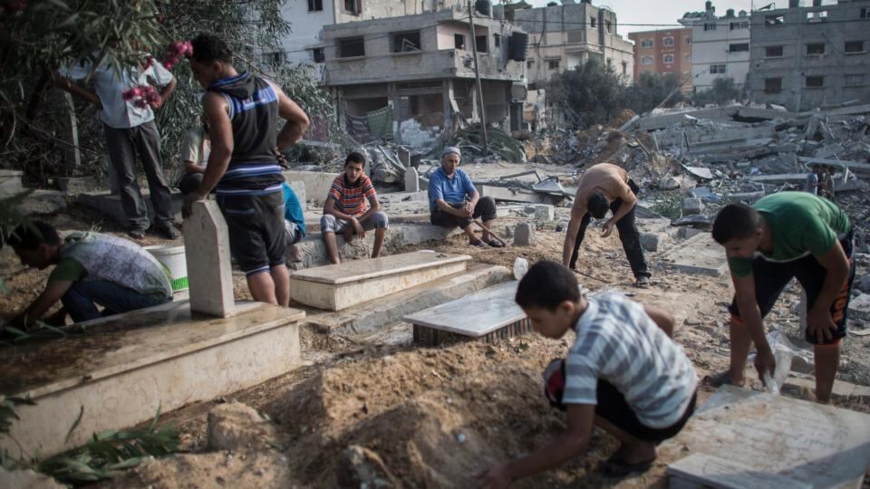 A Palestinian man looks on while others clean up graves from debris from a nearby house which was destroyed during an Israeli airstrike. Photograph: Oliver Weiken/EPA A Palestinian man looks on while others clean up graves from debris from a nearby house which was destroyed during an Israeli airstrike. Photograph: Oliver Weiken/EPA