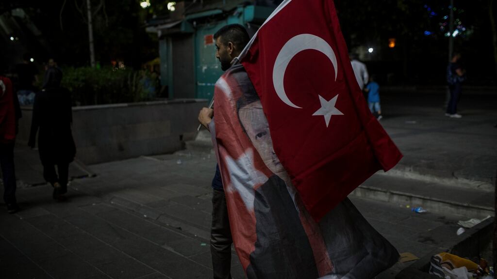 A man wears a flag bearing Turkish president Recep Tayyip Erdogan’s face during a rally two nights after a coup attempt in Ankara, Turkey. Photograph: Nicole Tung/The New York Times