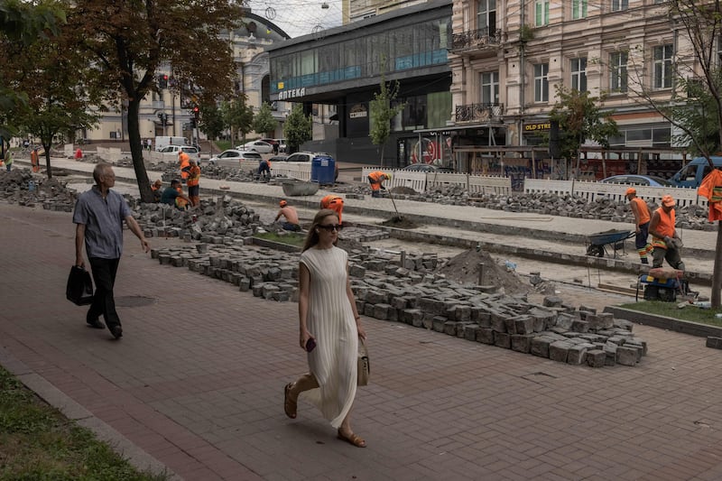 People walk past communal workers repairing a cobblestone road in downtown Kyiv on August 2nd. Photograph: Roman Pilipey/AFP via Getty