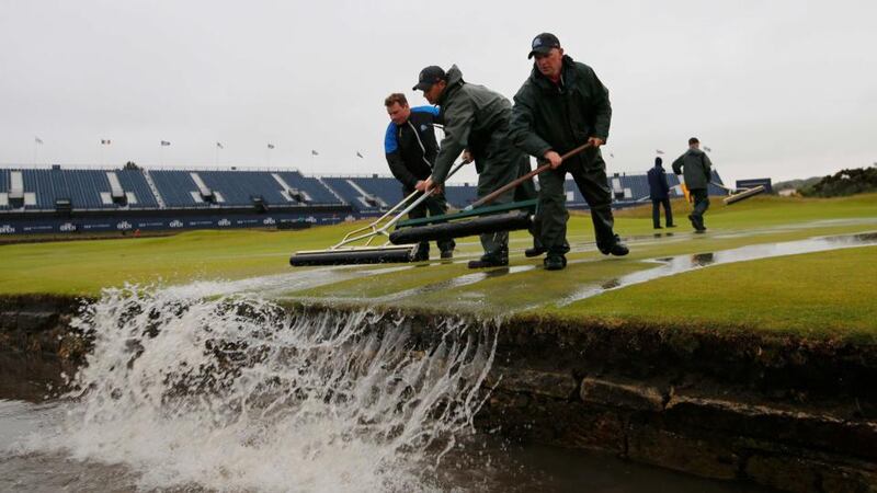 Groundstaff remove water from the first green after torrential rain forced play to be suspended. Photograph: Paul Childs/Reuters