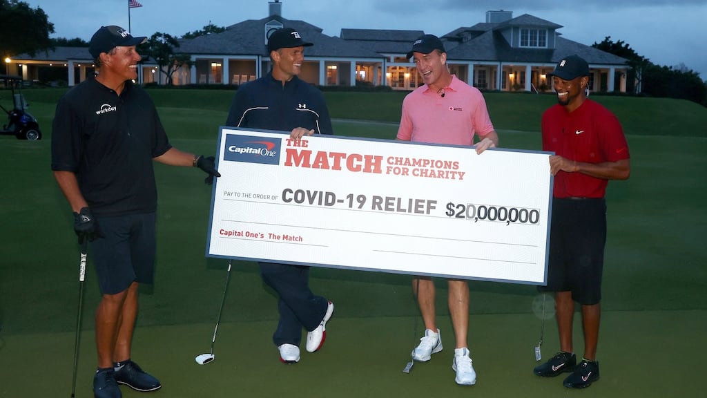 Phil Mickelson, Tom Brady, Peyton Manning and Tiger Woods pose with the cheque after raising $20 million for charity. Photo: Mike Ehrmann/Getty Images
