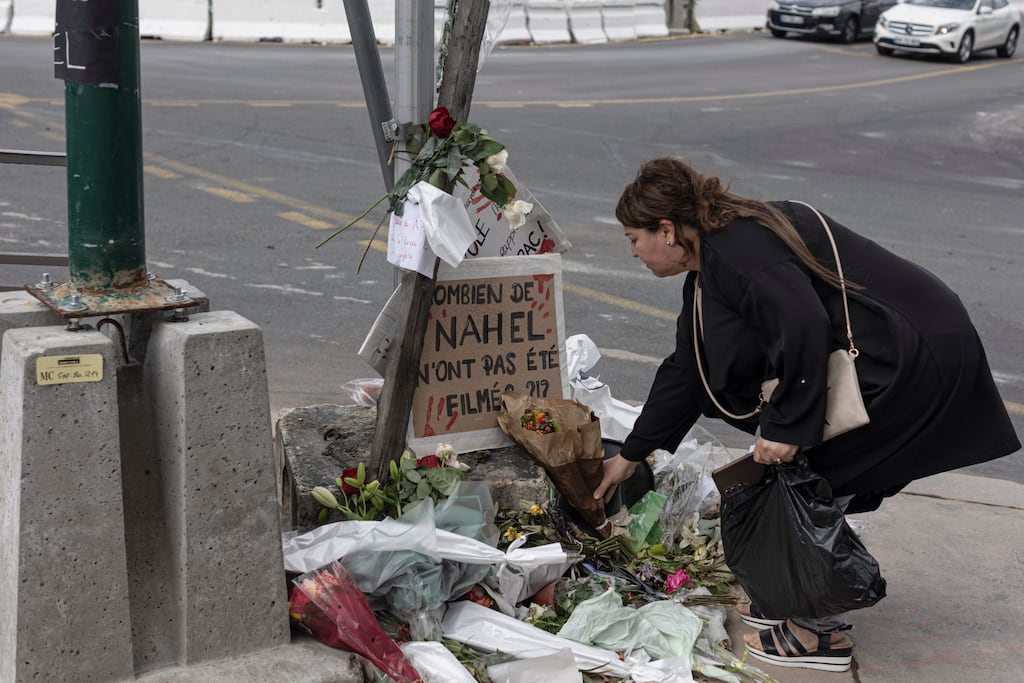 A woman pays her respects at the site where Nahel M died, shortly after his funeral, on July 1st in Nanterre, France. Nahel M was a French teenager of North African origin was shot dead by police on June 27th, the third fatal traffic stop shooting this year in France, causing nationwide unrest and clashes with police forces. Photograph: Sam Tarling/Getty