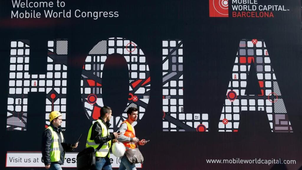 Workers walk past a Mobile World Congress banner in Barcelona. The GSMA Mobile World Congress will take place this week. Photograph: Reuters
