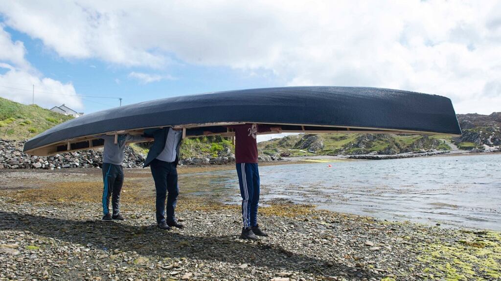 Walking the currachs to the short on Inishbofin, Co Donegal.