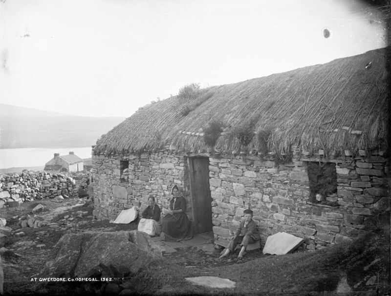 People sit outside a house at Gweedore, Co Donegal. By Robert French, dated circa 1880-1900. Photograph: National Library of Ireland/Flickr commons