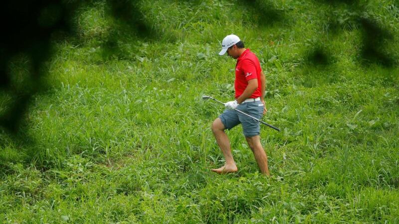 Jason Day of Australia walks back to his socks and shoes after hitting his ball from the rough on the other side of a creek after his drive off the second tee. Photo: Brian Snyder/Reuters
