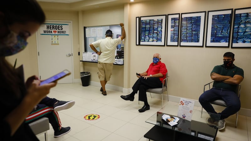 People wearing protective masks sit in a waiting room during clinical trials for a Covid-19 vaccine in Florida.