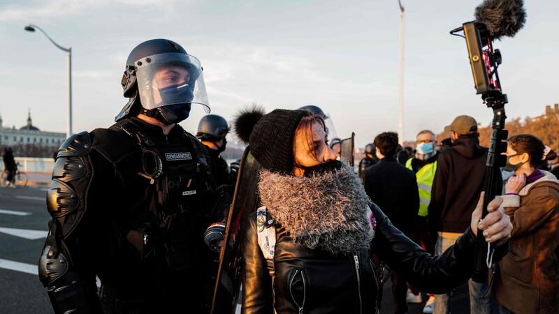 A woman films anti-riot police as she takes part in a demonstration against article 24 in Lyon. Photograph: Olivier Chassignole/AFP via Getty Images