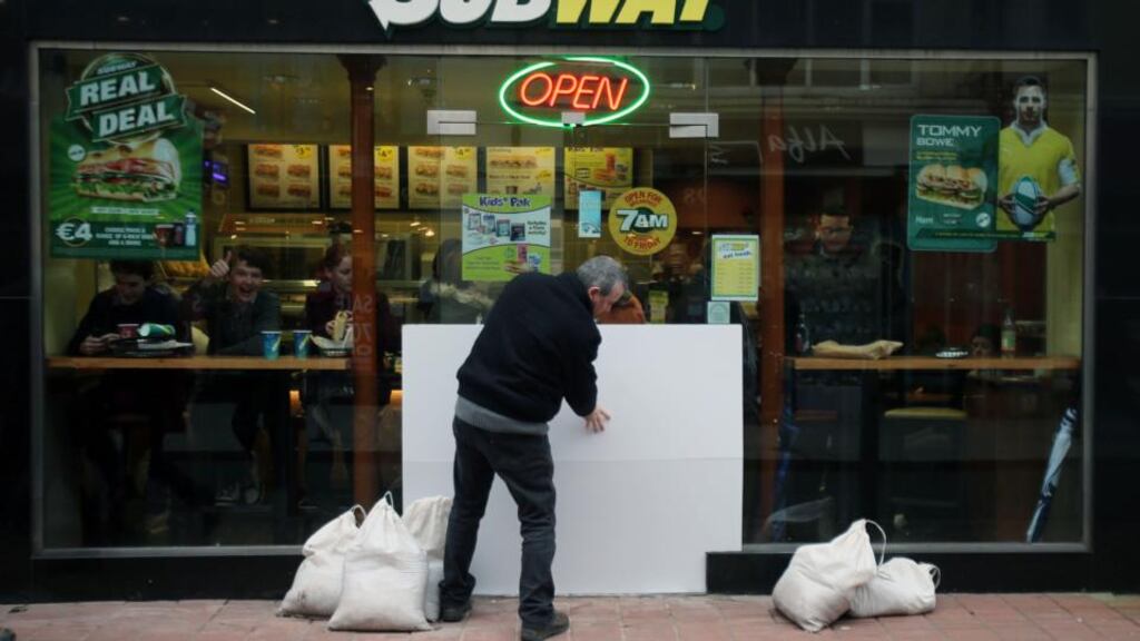 A shopkeeper in Cork city centre preparing for flooding yesterday evening. Photograph: Niall Carson/PA