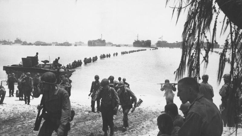 Army reinforcements disembarking from LSTs form a graceful curve as they proceed across coral reef toward the beach at Saipan in summer 1944 Saipan.