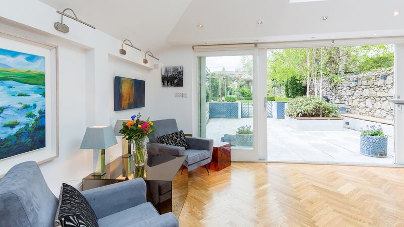 Glazed doors open out to a patio with built-in seating and a barbecue area with Belfast sink