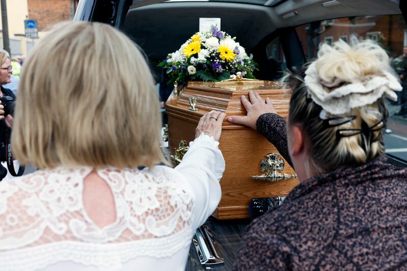 Mourners pay their respects by touching the coffin of Br Kevin Crowley. Photograph: PA