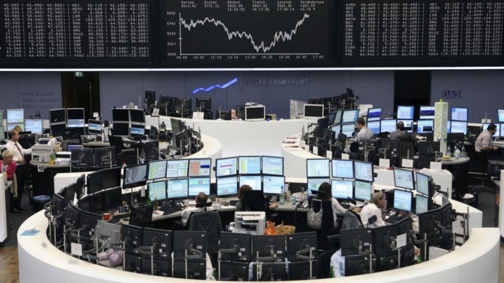 Financial traders work at their computers beneath a display of the DAX Index curve at the Frankfurt Stock Exchange. European shares fell on Friday, led lower by a drop in Germany’s DAX index. Photo: Bloomberg